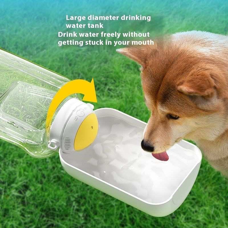 Dog drinking water from a pet water bottle on grass