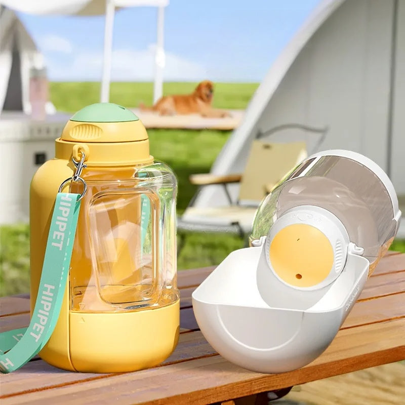Yellow water bottle with green cap and white travel mug on a wooden table outdoors.