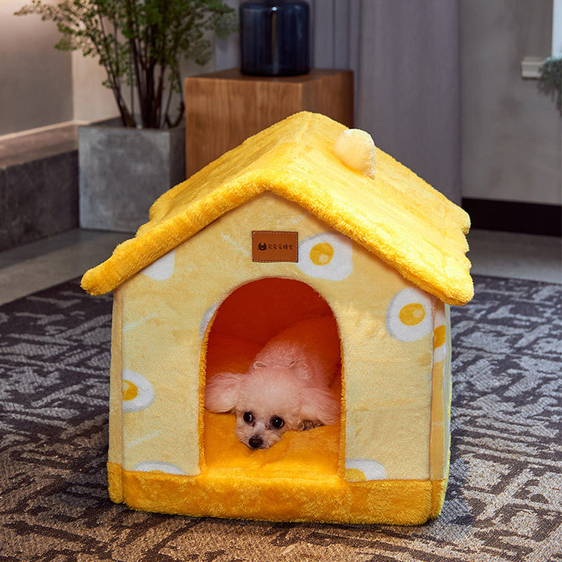 Yellow plush pet house with polka dot design and pom-pom detail on the roof, featuring a small white dog resting inside.