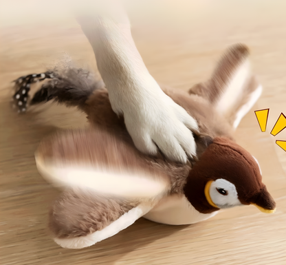 Plush penguin toy on a wooden surface with a hand petting it