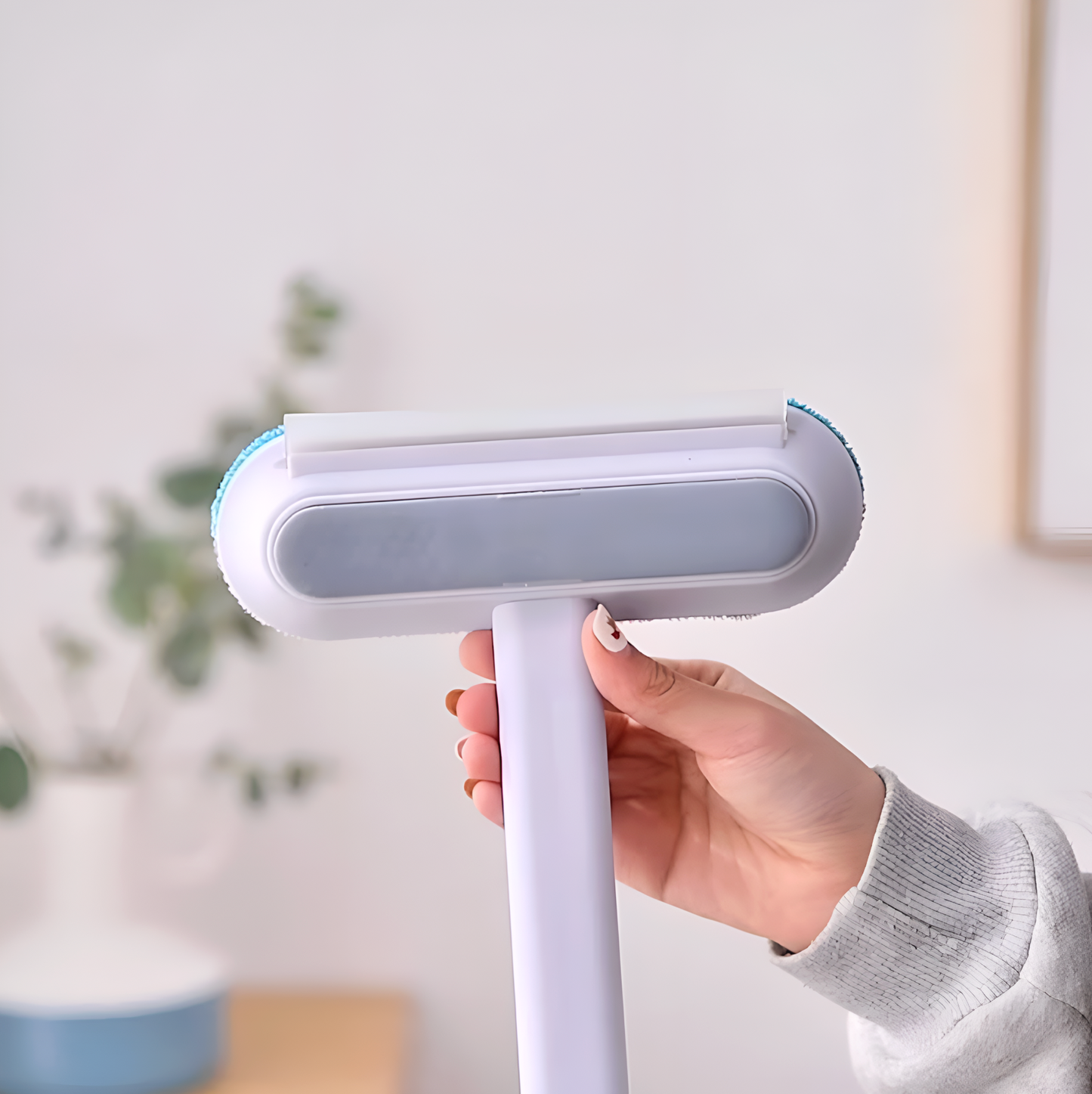 Hand holding a white pet grooming brush with a blurred indoor background