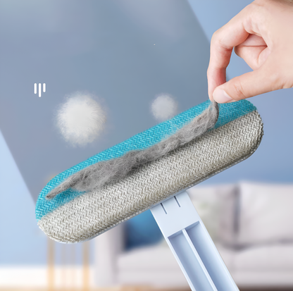 Cleaning tool with a fluffy head being held by a hand, with a blurred indoor background.