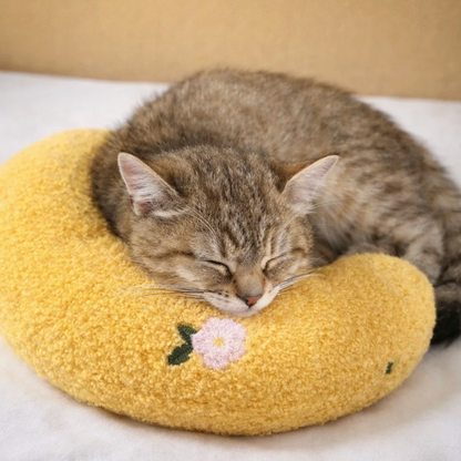 Cat sleeping on a yellow cushion with a floral design