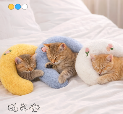 Three kittens sleeping on colorful cat-shaped pillows on a bed.